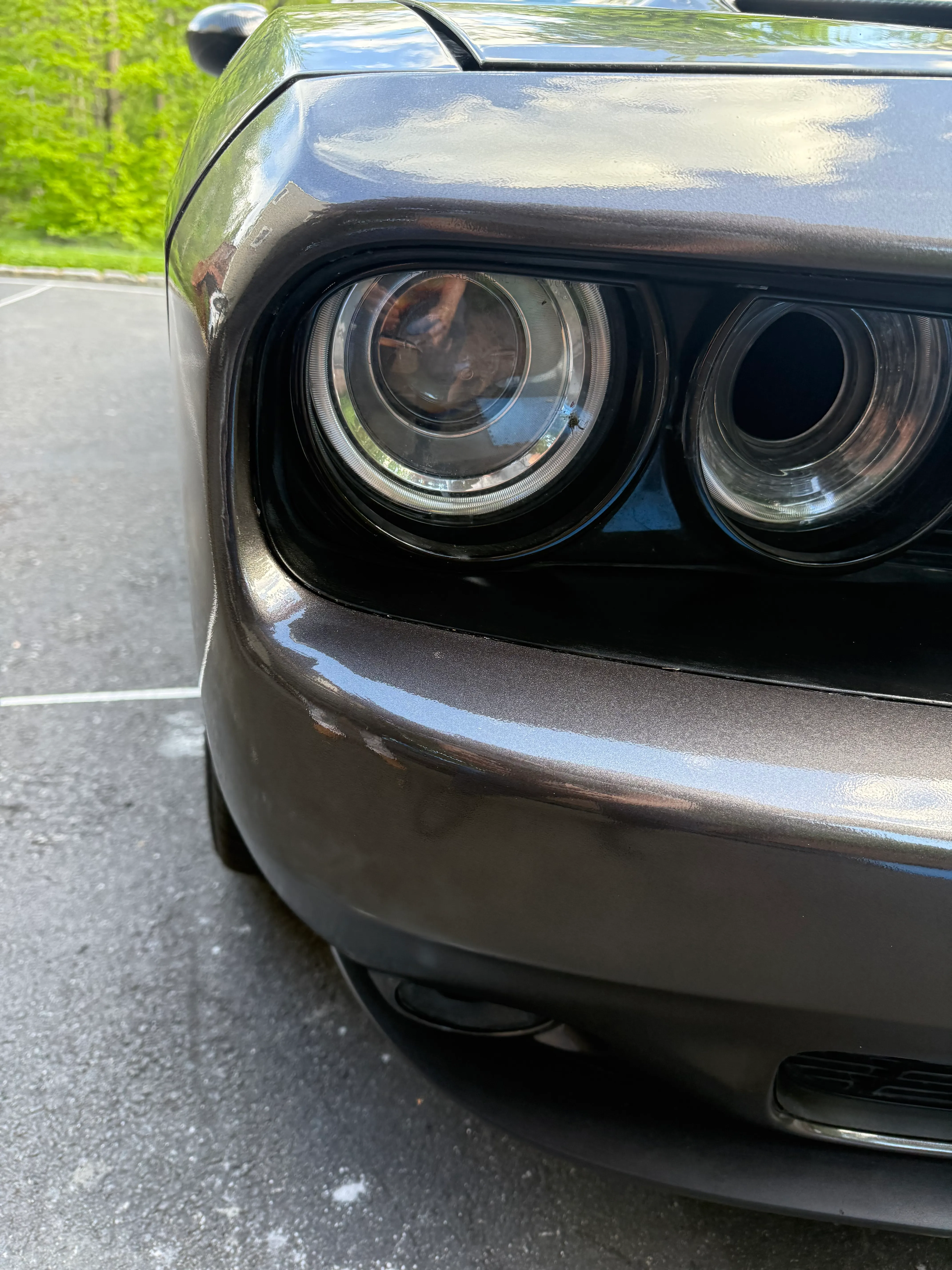 Same Dodge Challenger front bumper corner after repair, refinished and color-matched, smooth gloss paint.