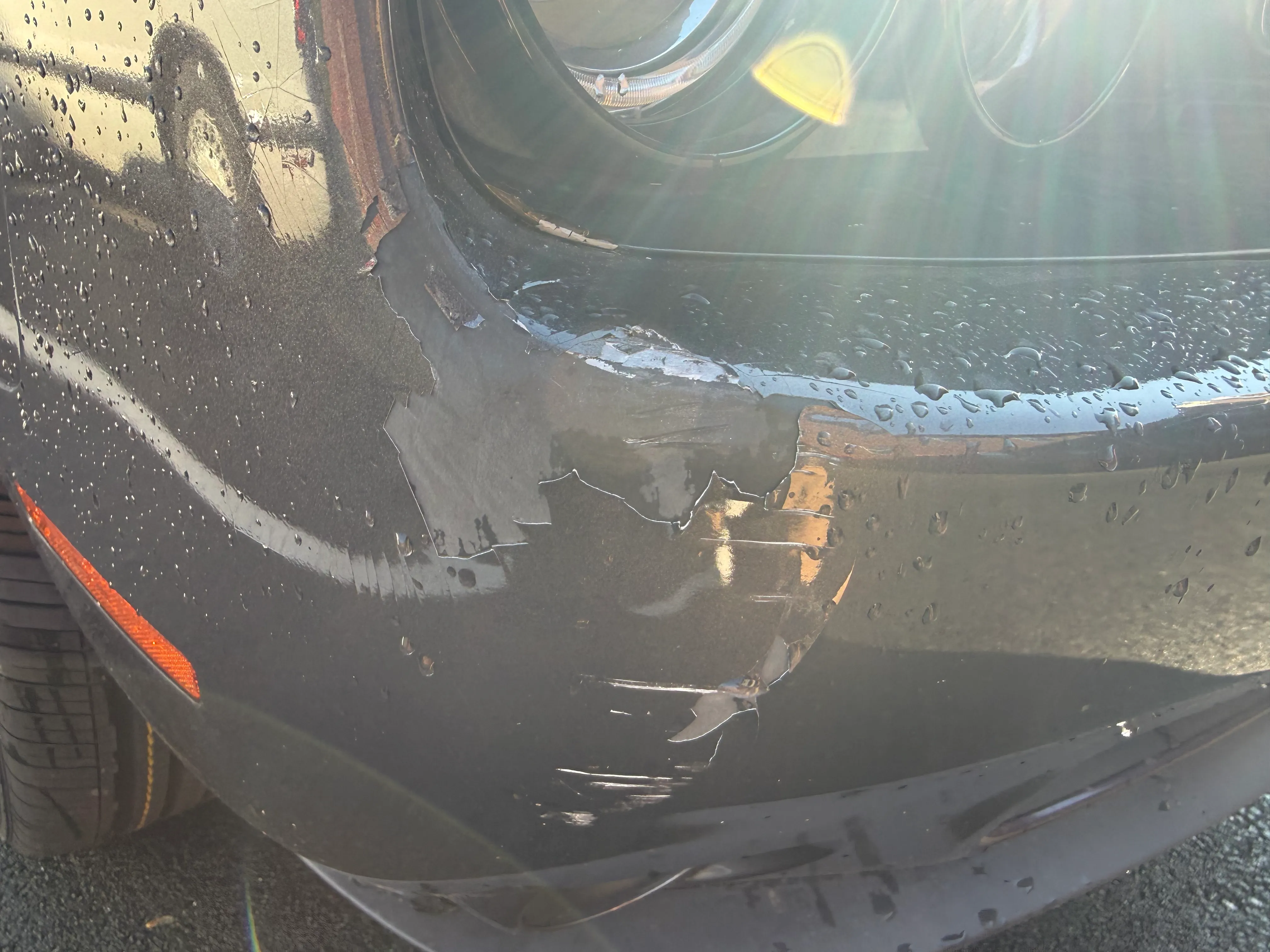 Closer view of the peeling paint on the Dodge Challenger front bumper before repair.